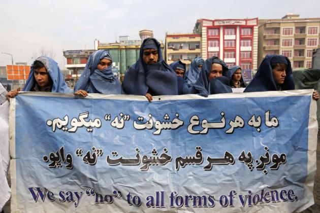 Male Afghan women's rights activists wearing burqas hold up banner to show solidarity to Afghan women ahead of International Women's Day in Kabul